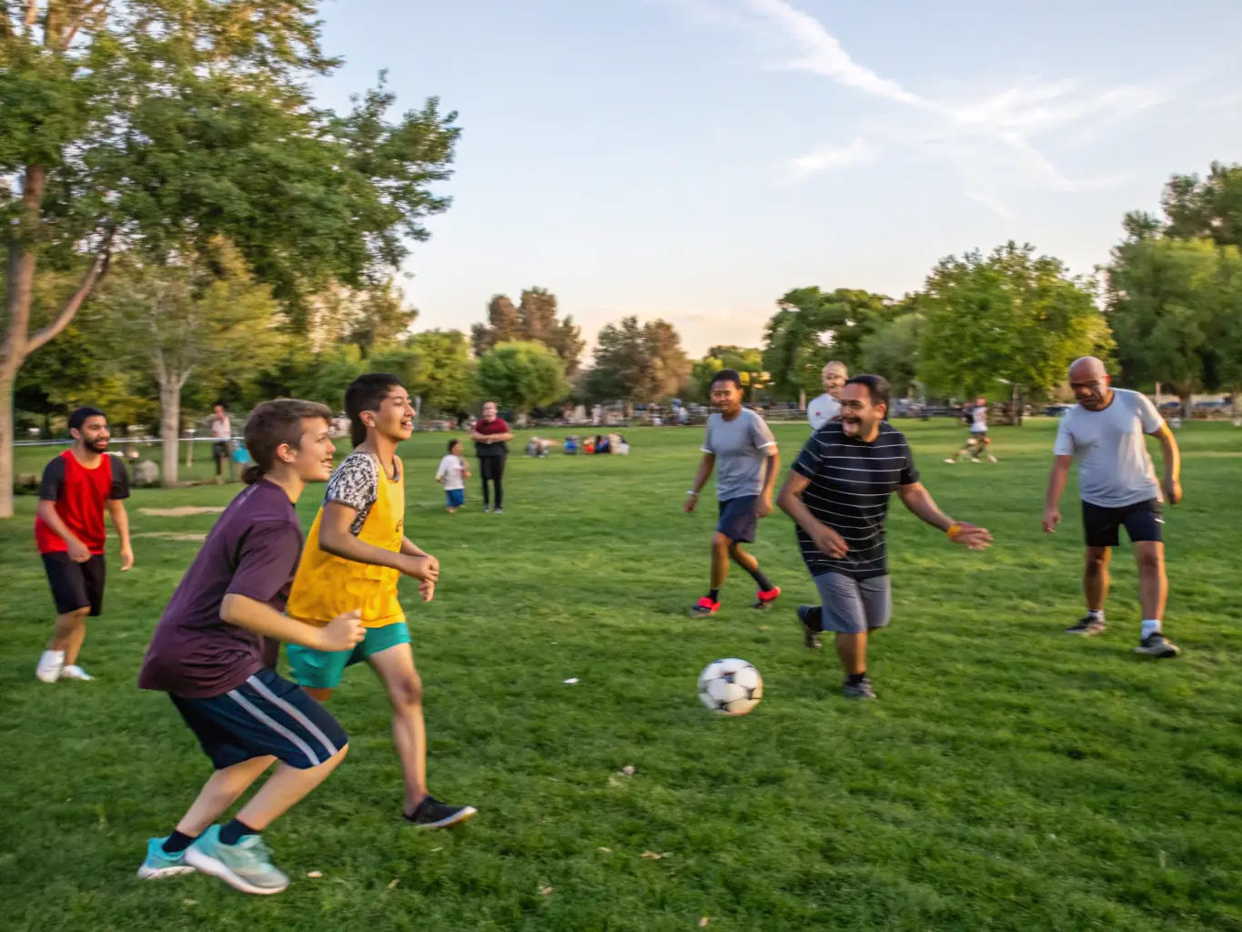 An image of children and adults participating in a local soccer match in a community park, representing the Community Sports Programs.